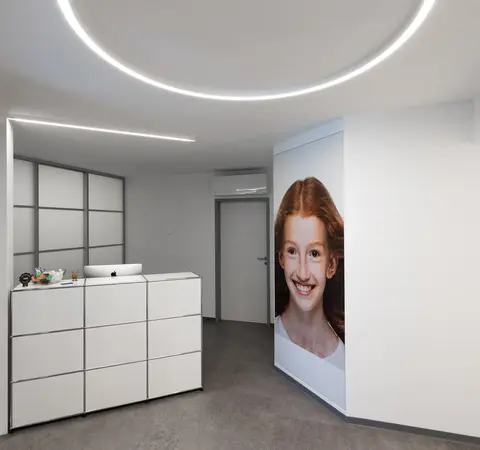 Moderner Empfangsbereich einer Zahnarztpraxis mit großem Kinderfoto an der Wand.