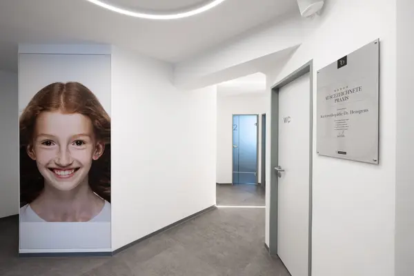 Moderner Flur in einer Kieferorthopädie mit großem Kinderfoto und Auszeichnungsplakette.