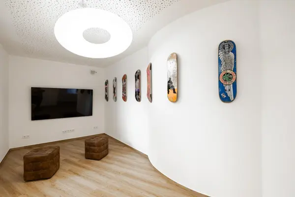 Moderner Wohnraum mit Skateboard-Dekoration, Flachbildfernseher und Sitzhockern.