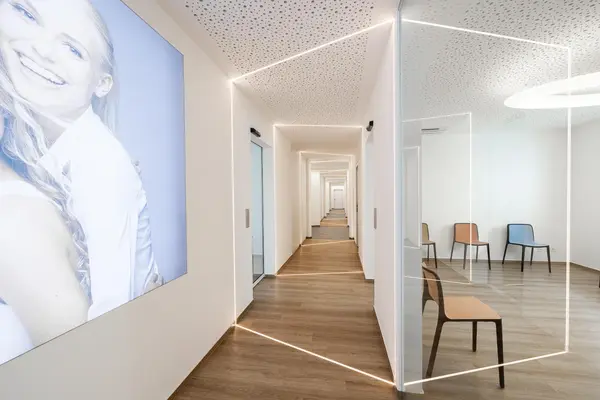 Moderner Flur einer Zahnarztpraxis mit Wartebereich, Holzfußboden und heller Beleuchtung.