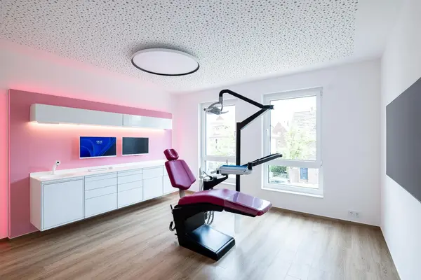 Modernes Zahnarztpraxis-Behandlungszimmer mit heller Einrichtung und ergonomischem Behandlungsstuhl.